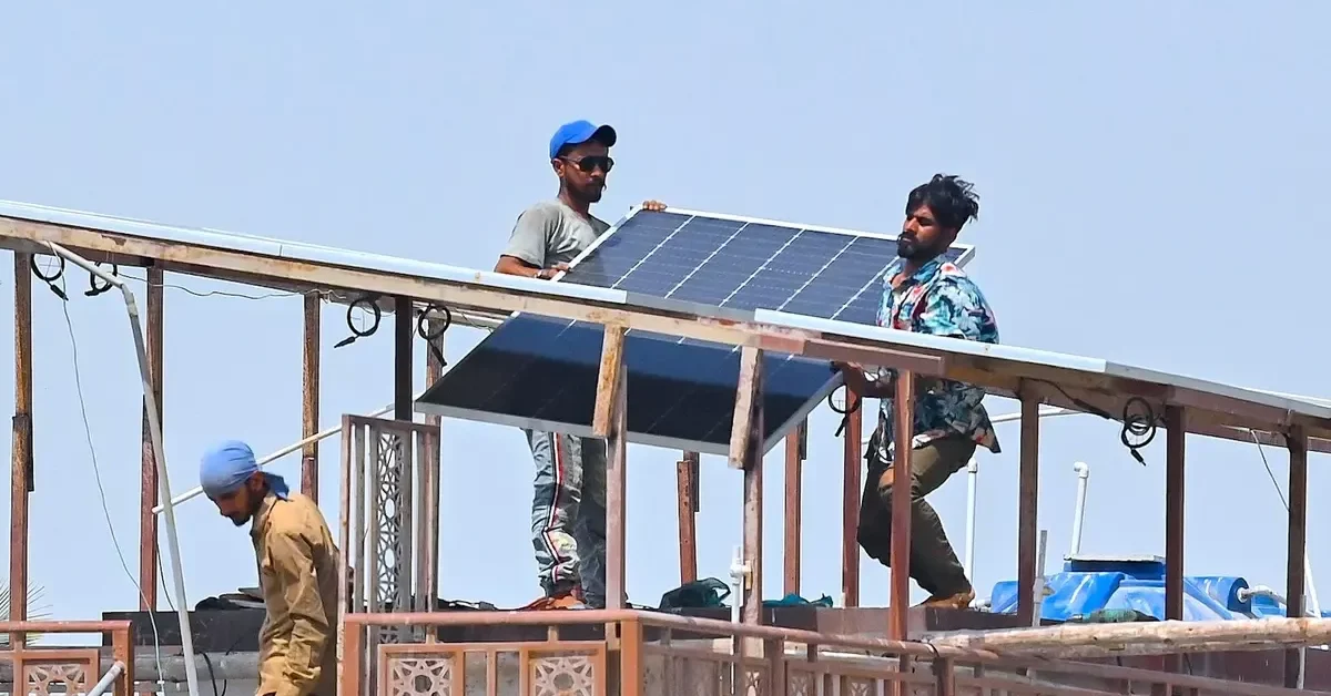 Technicians install rooftop solar panels in Karachi, Pakistan] Image source: Yale Environment 360