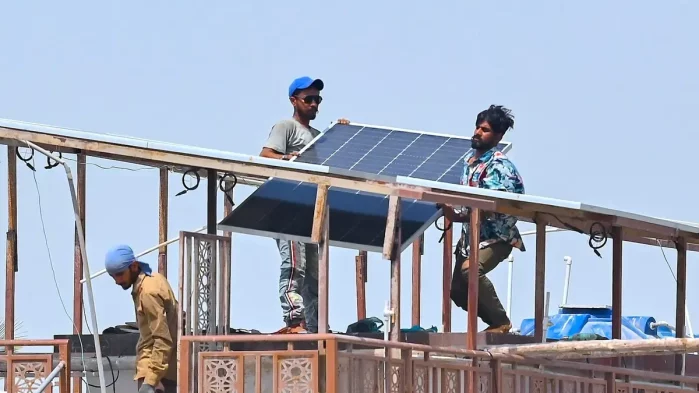 Technicians install rooftop solar panels in Karachi, Pakistan] Image source: Yale Environment 360