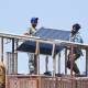 Technicians install rooftop solar panels in Karachi, Pakistan] Image source: Yale Environment 360